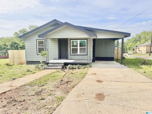 view of front of home with driveway, covered porch, fence, and an attached carport