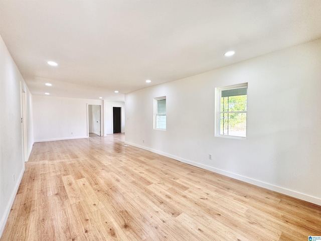 empty room with light wood-style floors, recessed lighting, and baseboards