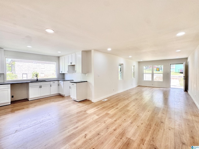 kitchen featuring a sink, light wood-type flooring, open floor plan, dark countertops, and recessed lighting