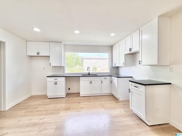 kitchen featuring a sink, light wood-style flooring, white cabinets, dark countertops, and recessed lighting