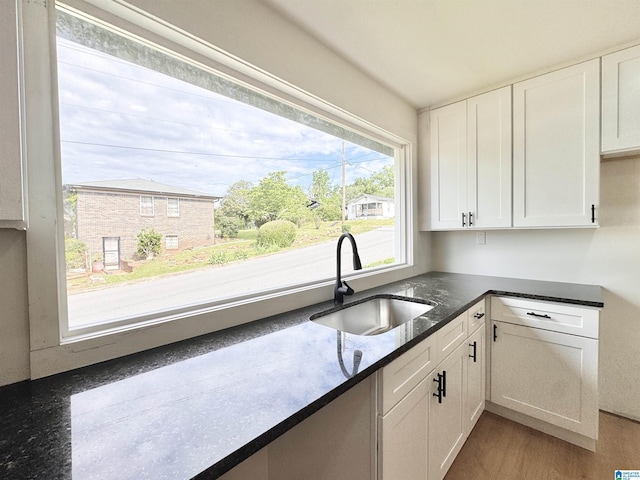 kitchen featuring a sink, white cabinetry, and dark stone countertops
