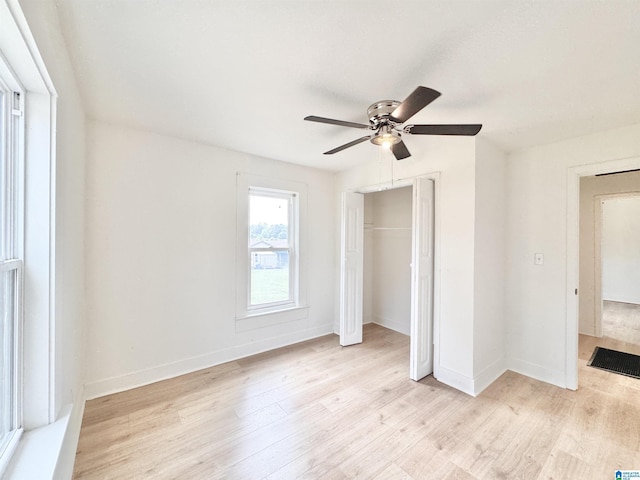 unfurnished bedroom featuring light wood-type flooring, a closet, baseboards, and a ceiling fan
