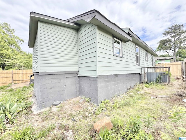 view of side of home featuring fence and crawl space