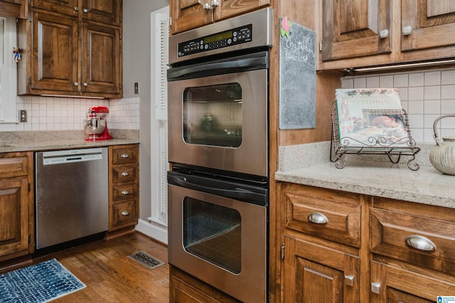 1209 29th St S, Birmingham, AL 35205 - kitchen with stainless steel appliances, decorative backsplash, dark wood finished floors, and light stone counters