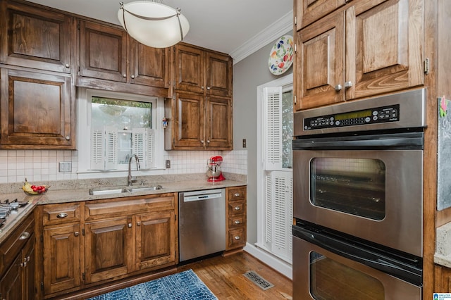 1209 29th St S, Birmingham, AL 35205 - kitchen with stainless steel appliances, a sink, crown molding, decorative backsplash, and wood finished floors