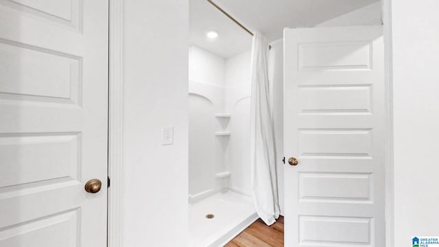 full bath with a stall shower and wood finished floors