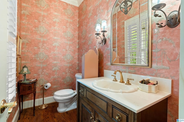 bathroom with wallpapered walls, wood finished floors, toilet, baseboards, and vanity