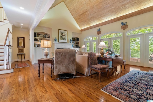 living room with built in shelves, stairs, light wood-style flooring, a fireplace, and recessed lighting
