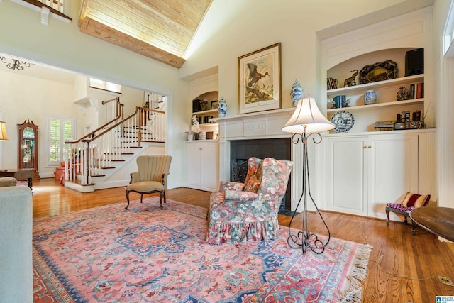 living area with built in features, wood finished floors, stairs, lofted ceiling, and a fireplace