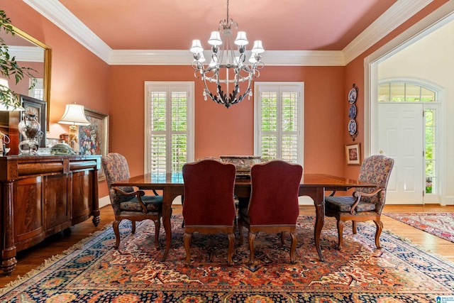 dining area with plenty of natural light, a chandelier, wood finished floors, and ornamental molding