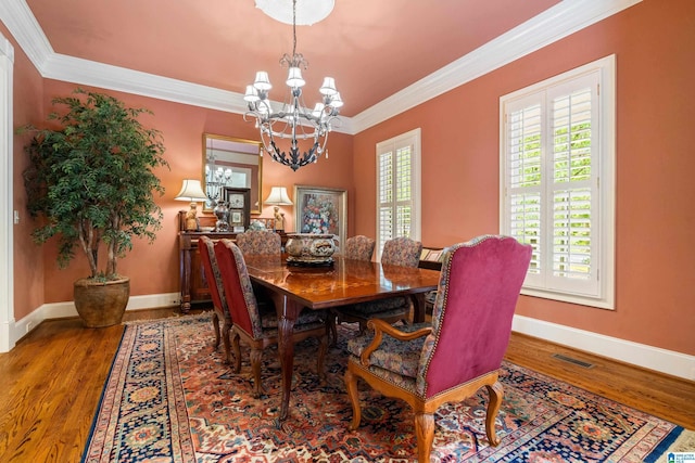 dining space featuring a chandelier, crown molding, baseboards, and wood finished floors