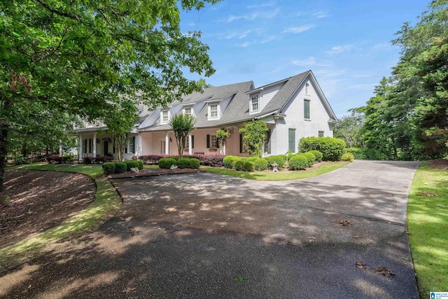 cape cod house with curved driveway and a porch