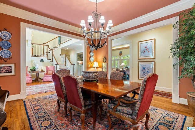 dining room featuring a chandelier, stairway, ornamental molding, baseboards, and wood finished floors