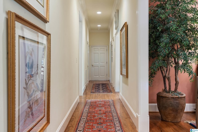 hallway featuring light wood-style flooring, baseboards, crown molding, wallpapered walls, and recessed lighting