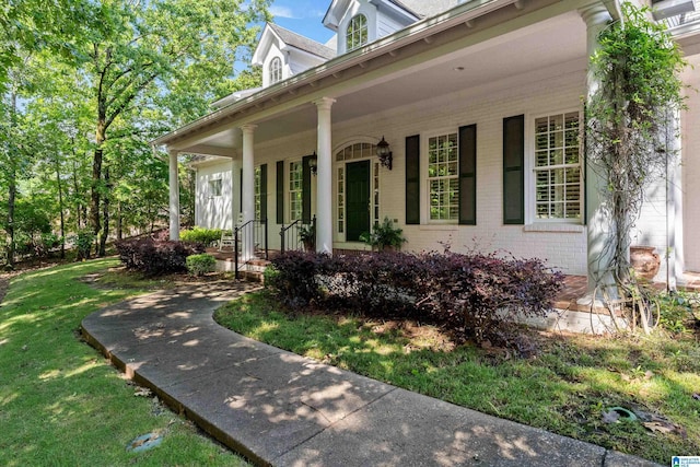 property entrance with brick siding, a porch, and a yard