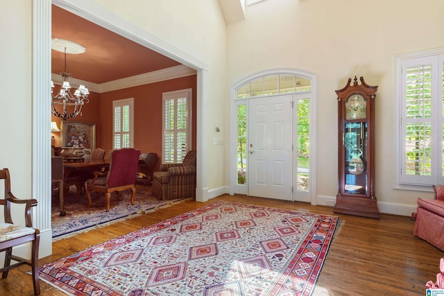 foyer with a chandelier, healthy amount of natural light, wood finished floors, and ornamental molding