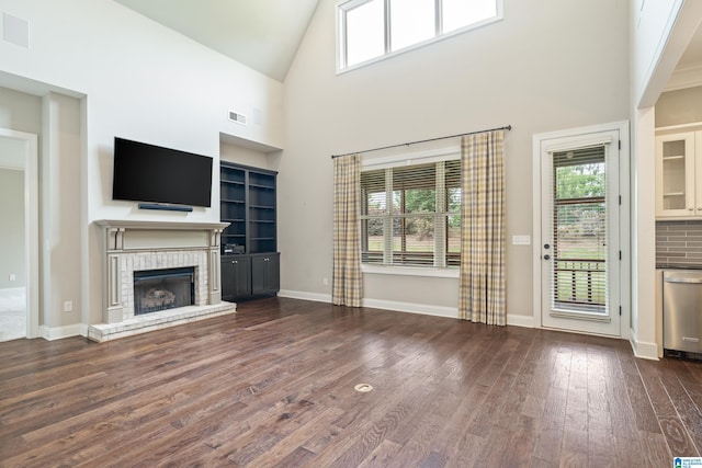 unfurnished living room with dark wood finished floors, a fireplace, high vaulted ceiling, built in shelves, and baseboards