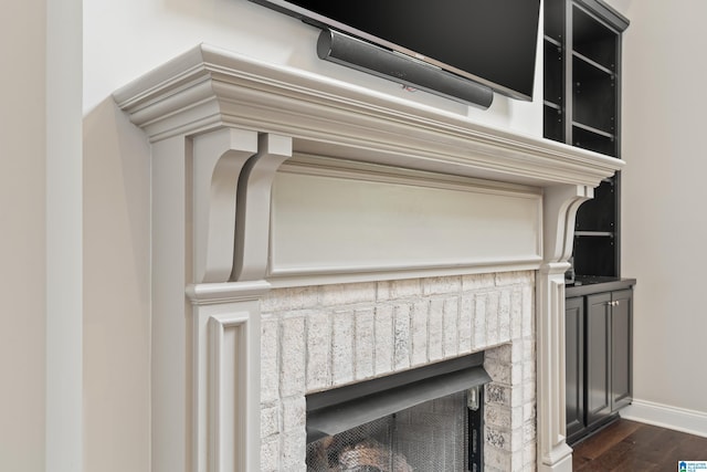 detailed view of wood finished floors, a fireplace, and baseboards