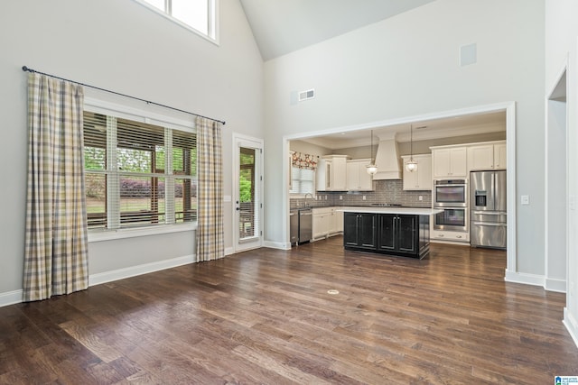 kitchen with stainless steel appliances, custom range hood, high vaulted ceiling, healthy amount of natural light, and tasteful backsplash