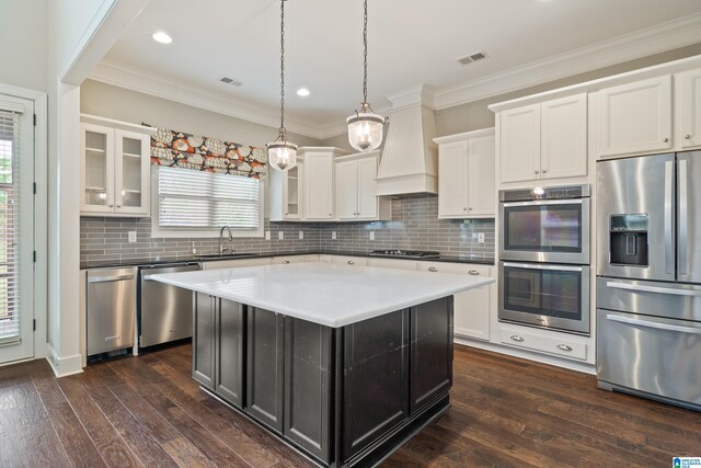 kitchen featuring appliances with stainless steel finishes, a sink, glass insert cabinets, tasteful backsplash, and dark wood-style flooring