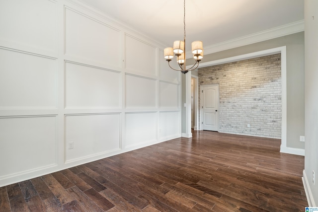 unfurnished dining area with brick wall, a chandelier, dark wood-style flooring, crown molding, and baseboards