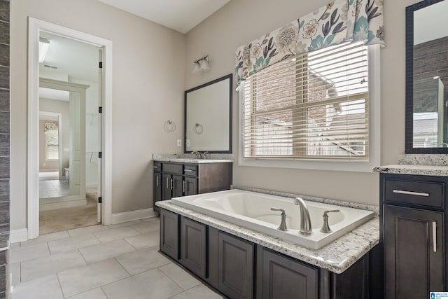 full bath featuring healthy amount of natural light, vanity, a bath, and baseboards