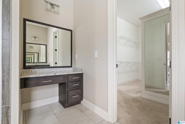 bathroom with vanity, baseboards, and a spacious closet