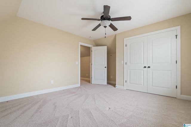 unfurnished bedroom featuring vaulted ceiling, carpet, a closet, baseboards, and ceiling fan