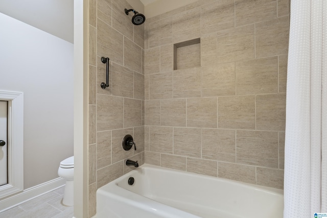 bathroom with toilet, shower / bathtub combination with curtain, and baseboards