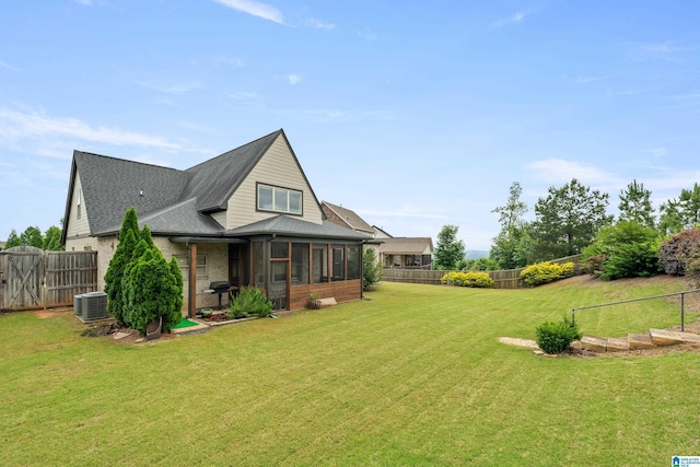 rear view of house featuring a sunroom, central AC unit, and a shingled roof
