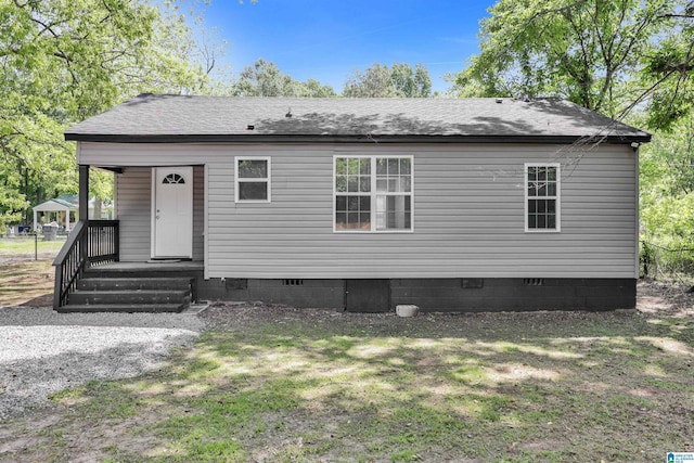 back of house featuring crawl space, a lawn, and roof with shingles