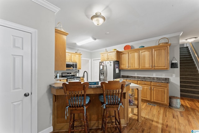 13688 Remlap Dr, Remlap, AL 35133 - kitchen with appliances with stainless steel finishes, a peninsula, ornamental molding, a kitchen bar, and light wood finished floors