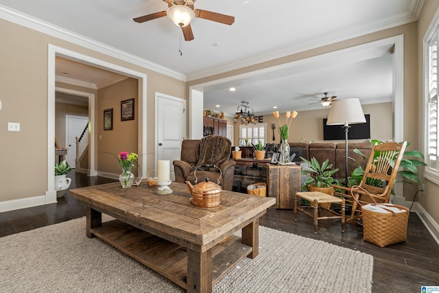 living area featuring ceiling fan, baseboards, dark wood finished floors, stairway, and crown molding