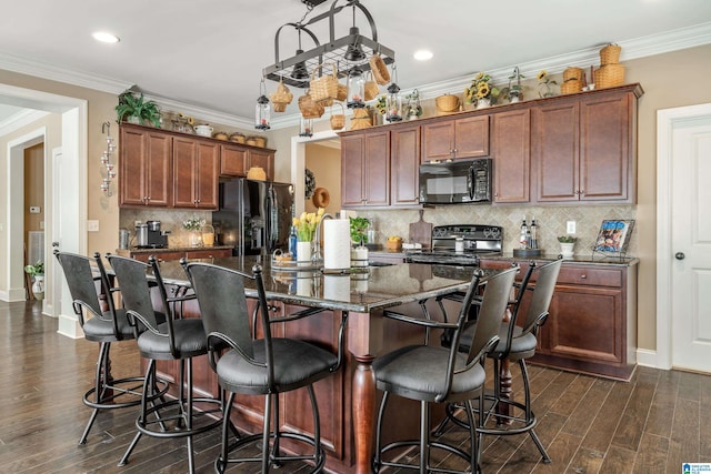 kitchen with black appliances, dark wood finished floors, a kitchen bar, a center island with sink, and recessed lighting