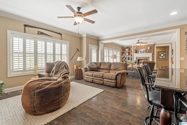 living area with ceiling fan, a fireplace, dark wood-style floors, crown molding, and baseboards