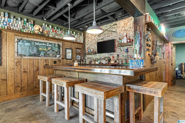 bar area featuring unfinished concrete floors and wooden walls