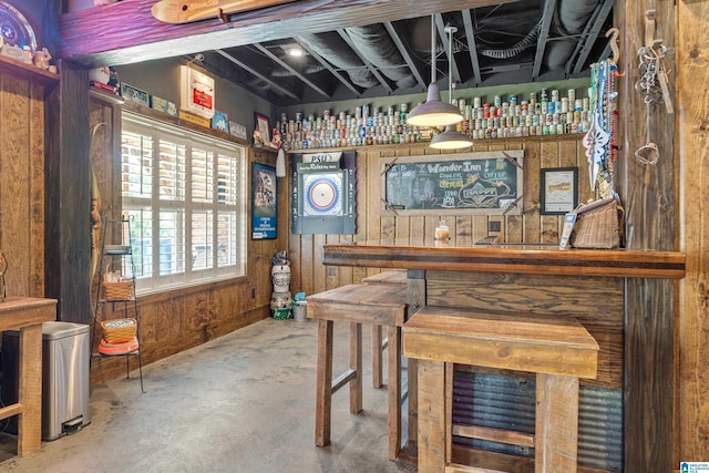 bar area featuring unfinished concrete floors and wooden walls