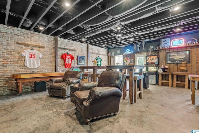 living area with concrete flooring and brick wall