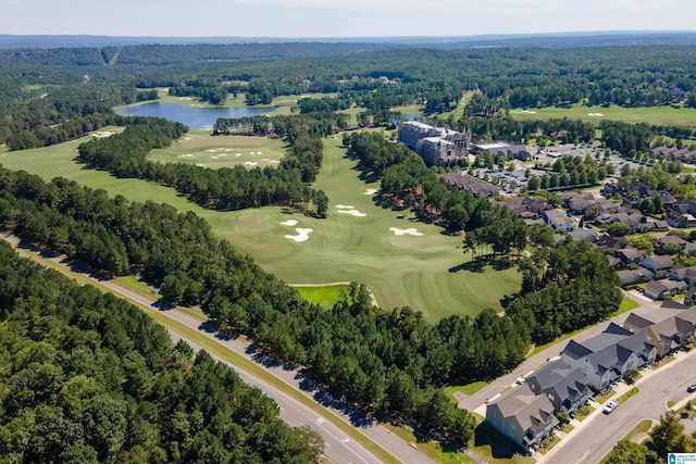 aerial view of property and surrounding area with a local golf course, a nearby body of water, a heavily wooded area, and nearby suburban area
