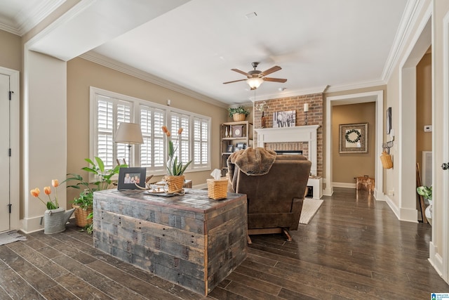 living room featuring a ceiling fan, dark wood finished floors, a brick fireplace, baseboards, and crown molding