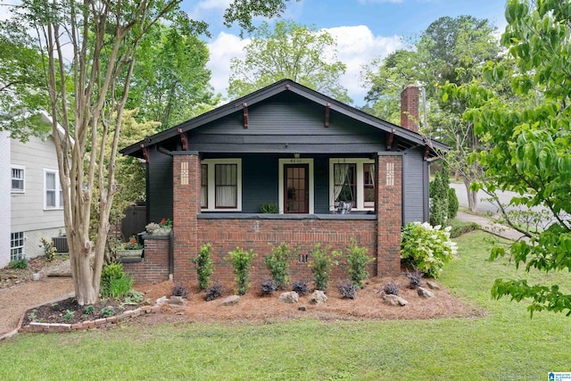 view of front of home featuring a chimney, a front yard, and brick siding