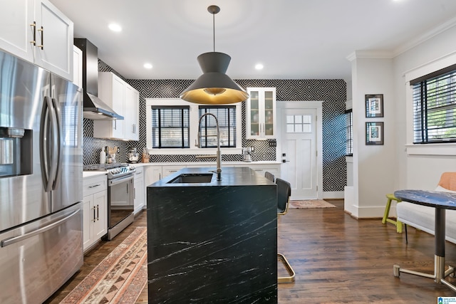 kitchen featuring appliances with stainless steel finishes, a sink, wall chimney range hood, ornamental molding, and light countertops