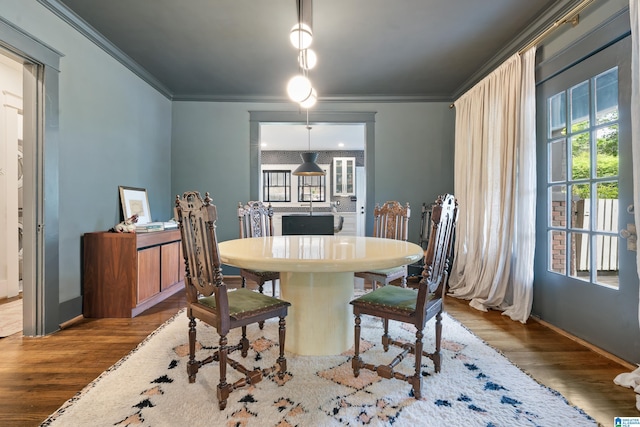 dining space featuring wood finished floors, crown molding, and baseboards