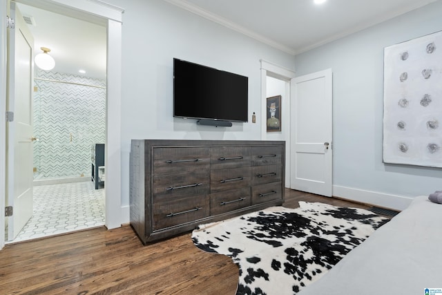 bedroom with dark wood-type flooring, ornamental molding, ensuite bathroom, and baseboards