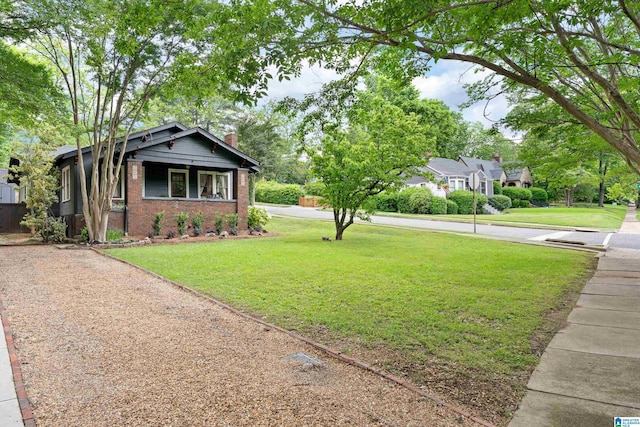 view of front of home with brick siding, a front lawn, and a chimney
