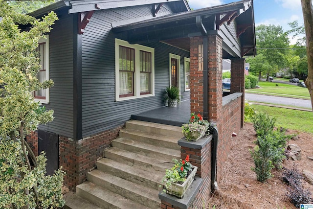 doorway to property with covered porch and brick siding