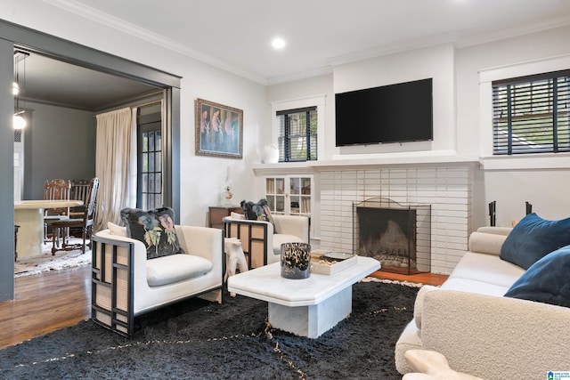 living room with wood finished floors, ornamental molding, a brick fireplace, and recessed lighting