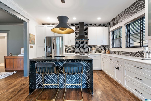 kitchen with stainless steel refrigerator with ice dispenser, wall chimney exhaust hood, white cabinetry, tasteful backsplash, and dark wood-style flooring