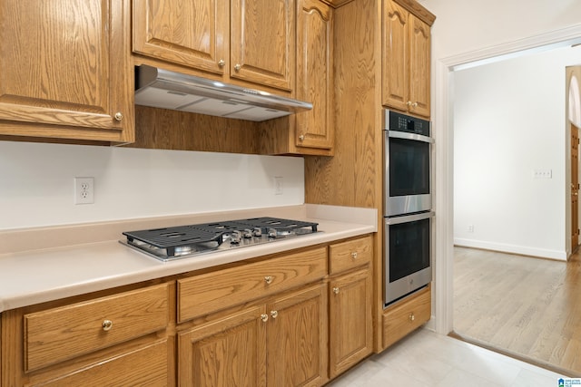 175 Sunhill Rd, Remlap, AL 35133 - kitchen with under cabinet range hood, appliances with stainless steel finishes, light countertops, brown cabinetry, and light tile patterned flooring