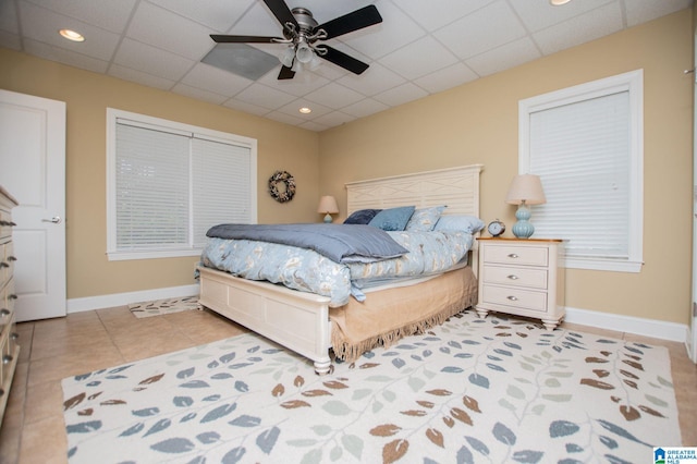 bedroom featuring baseboards, a drop ceiling, light tile patterned flooring, a ceiling fan, and recessed lighting